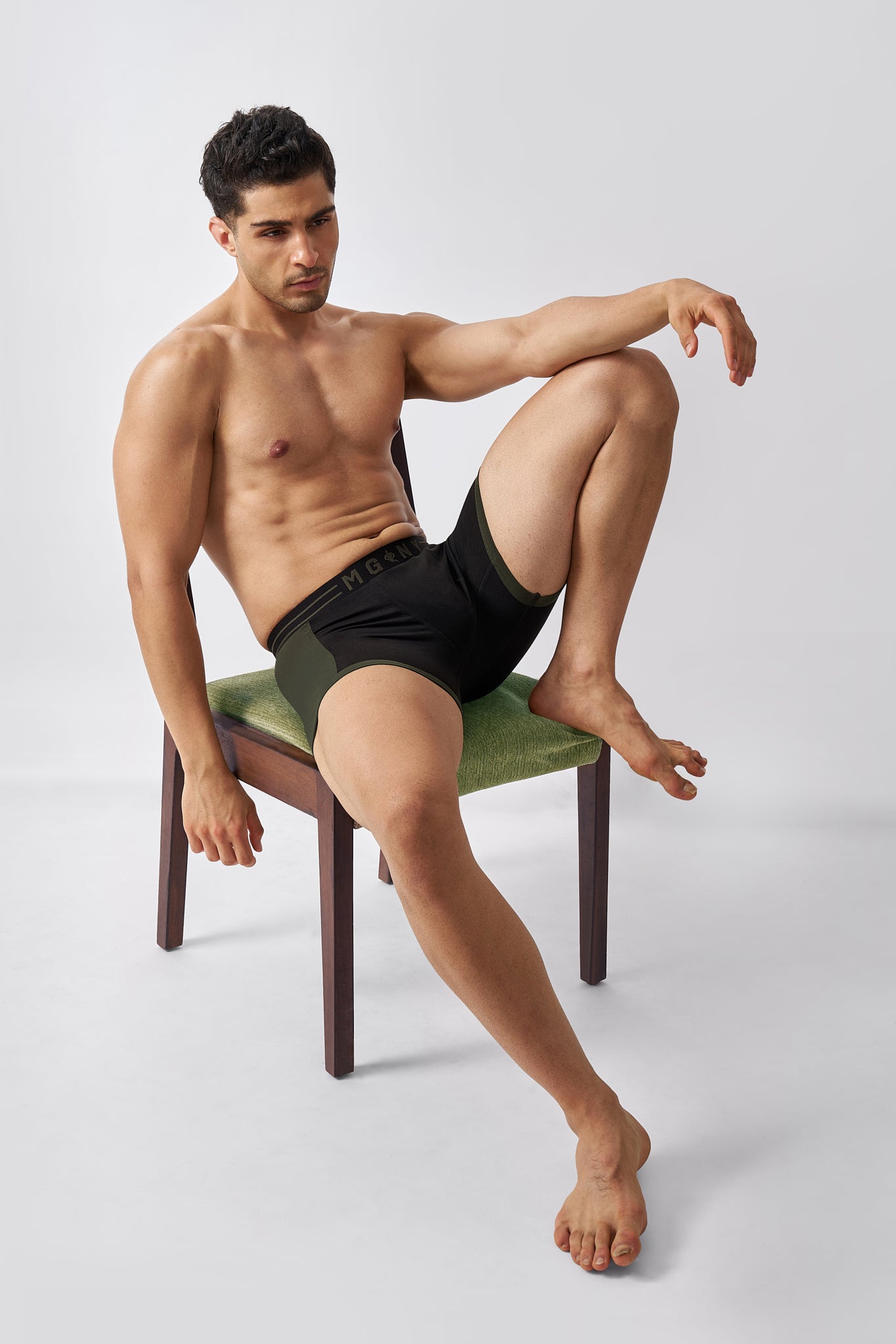 Man wearing Macho Genie black cotton boxer briefs in a relaxed seated pose